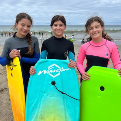Three teenage Nalu campers enjoying camp with boogie boards at Zuma beach in Malibu