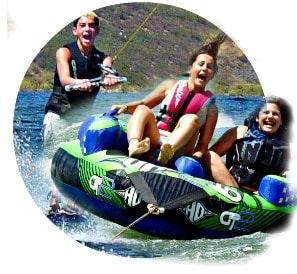 Three High Action Campers, two girls and one boy, laughing and smiling while enjoing Aloha Beach Camp's wakeboarding and innertubing activities at Castaic Lake.