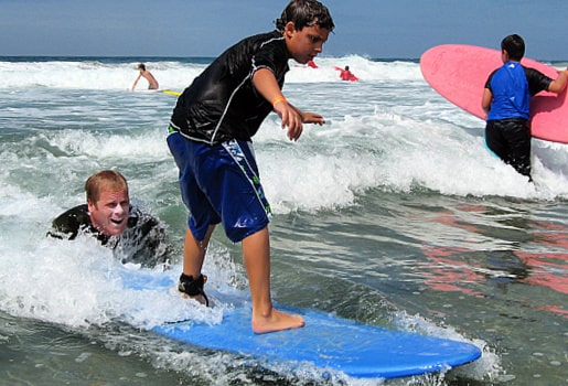 Teenage boy learning to surf from his camp counselor at Aloha Beach Camp's Zuma Beach location.